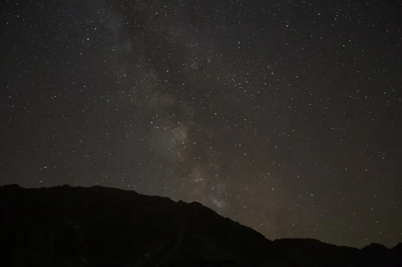 The Milky Way core rising behind a mountain ridge.